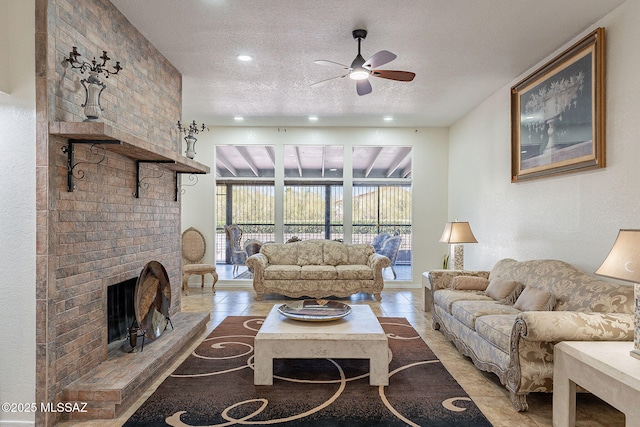 living room featuring ceiling fan, light tile patterned flooring, a textured ceiling, and a fireplace