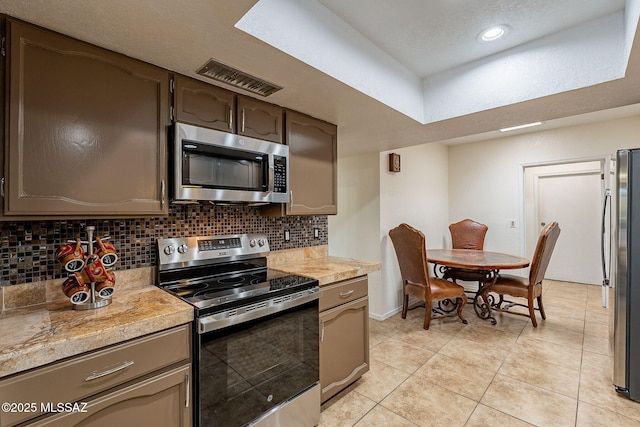 kitchen featuring light tile patterned floors, a textured ceiling, appliances with stainless steel finishes, and tasteful backsplash