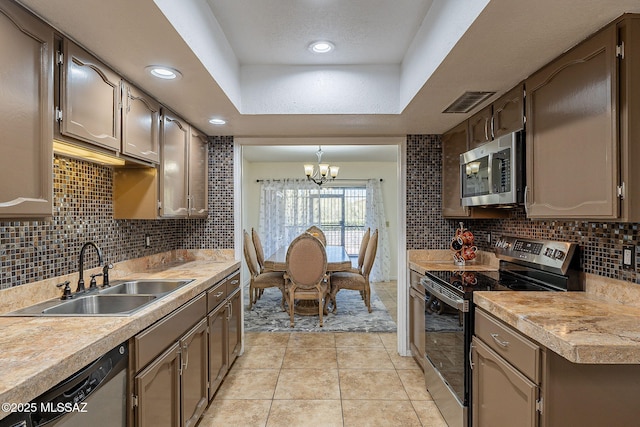 kitchen featuring sink, hanging light fixtures, stainless steel appliances, an inviting chandelier, and light tile patterned floors