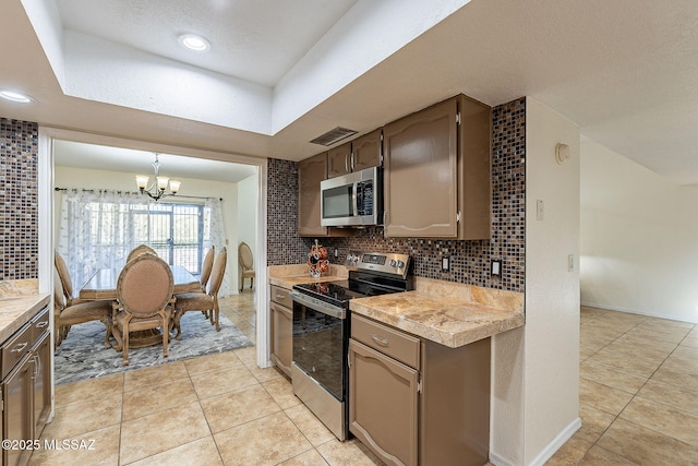 kitchen featuring decorative backsplash, light tile patterned flooring, stainless steel appliances, and an inviting chandelier