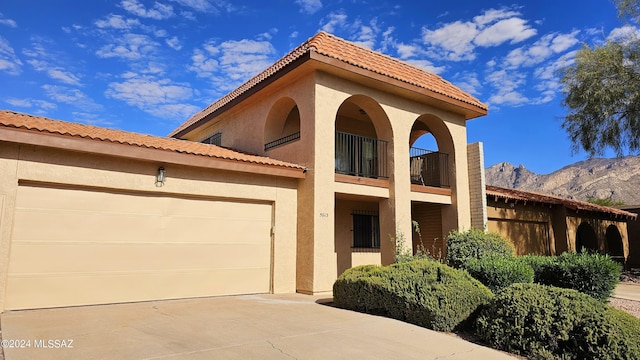 mediterranean / spanish-style home featuring a mountain view, a balcony, and a garage