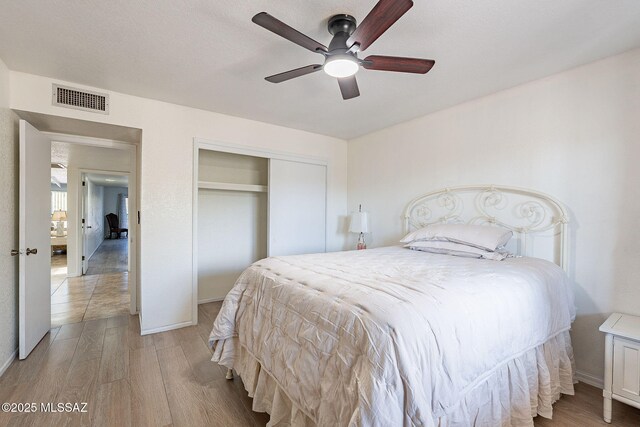 bedroom featuring ceiling fan, hardwood / wood-style floors, and a textured ceiling