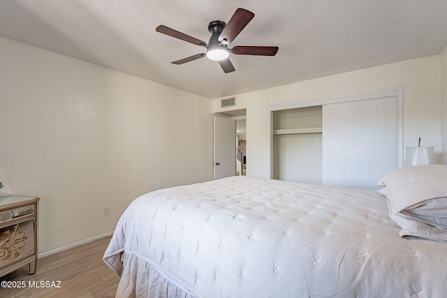 bedroom with a closet, light hardwood / wood-style flooring, and ceiling fan