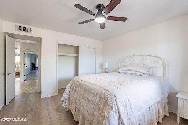 bedroom featuring ceiling fan, a closet, and light hardwood / wood-style floors