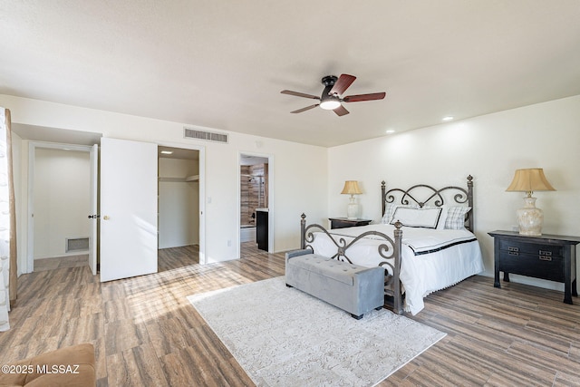 bedroom featuring a walk in closet, ceiling fan, a closet, and hardwood / wood-style floors