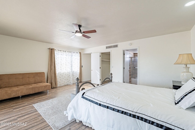 bedroom featuring hardwood / wood-style floors, ceiling fan, a textured ceiling, and ensuite bath