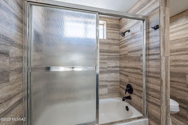 bathroom with toilet and combined bath / shower with glass door