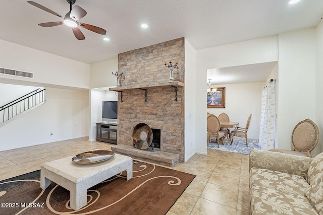 tiled living room featuring a fireplace and ceiling fan with notable chandelier