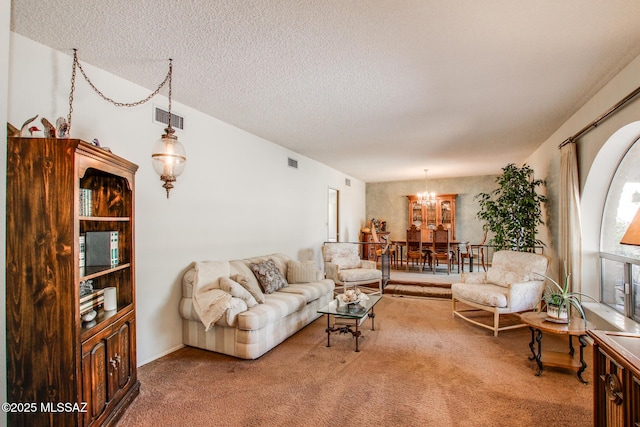 carpeted living room featuring a chandelier and a textured ceiling