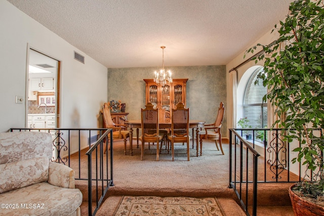 dining space featuring carpet floors, a textured ceiling, and an inviting chandelier