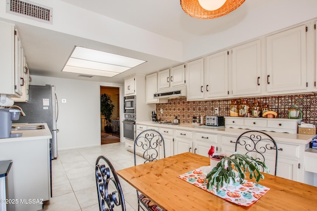 kitchen with white cabinetry, stainless steel microwave, and backsplash