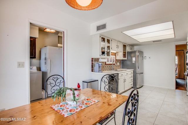 tiled dining space featuring washer / dryer and sink