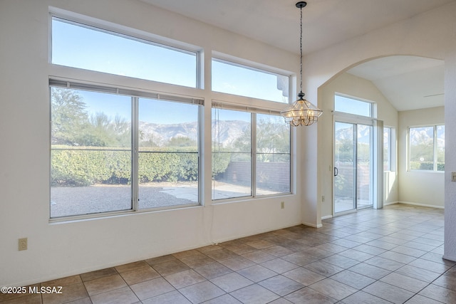 tiled spare room featuring a healthy amount of sunlight, a notable chandelier, and a mountain view