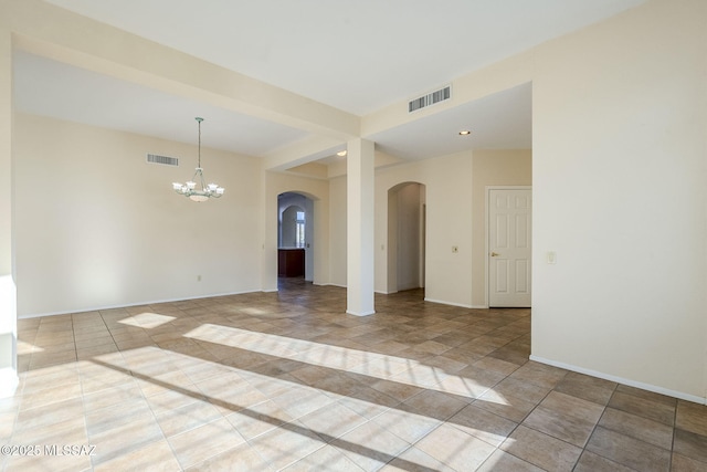 tiled spare room featuring an inviting chandelier