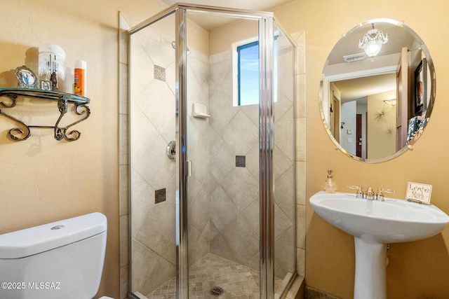 bathroom featuring an inviting chandelier, toilet, and a shower with door