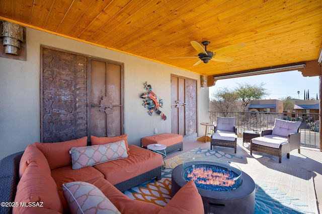 view of patio / terrace with ceiling fan and an outdoor living space with a fire pit