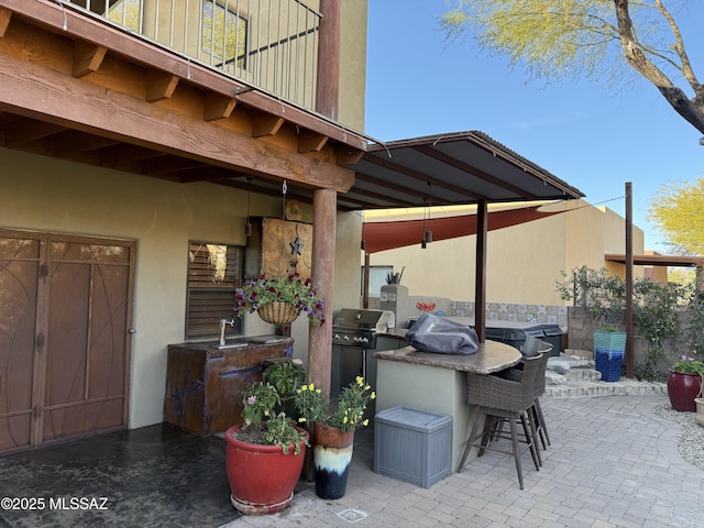 view of patio / terrace featuring a grill, a balcony, a bar, and exterior kitchen