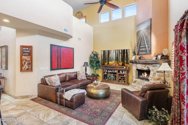 living room featuring a fireplace, a high ceiling, and ceiling fan