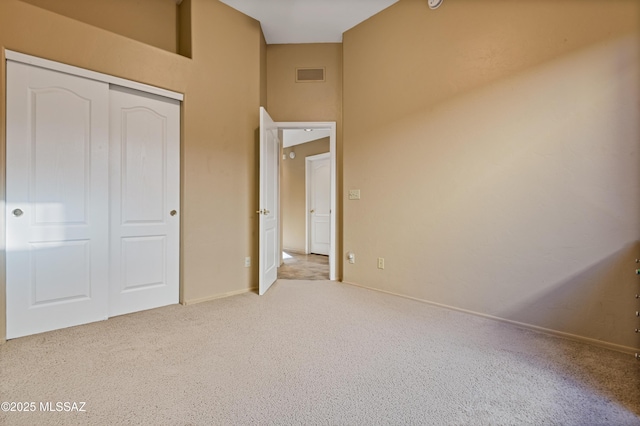 unfurnished bedroom with light carpet and a closet