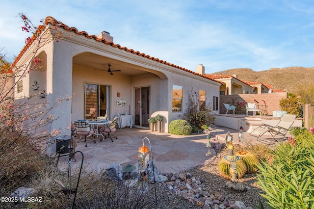 back of house with fence, a chimney, stucco siding, ceiling fan, and a patio area