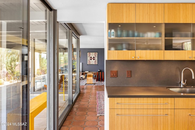 kitchen featuring dark tile patterned flooring, decorative backsplash, and sink