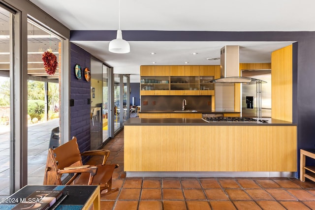 kitchen featuring island exhaust hood, kitchen peninsula, sink, decorative light fixtures, and stainless steel gas stovetop