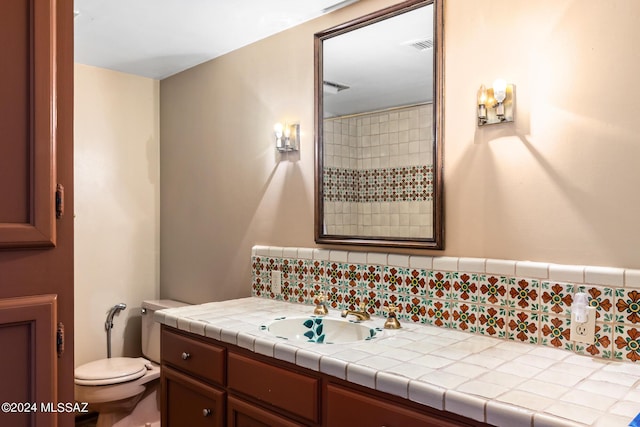 bathroom featuring vanity, toilet, and tasteful backsplash