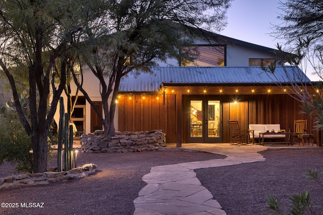 back house at dusk featuring french doors, an outdoor hangout area, and a patio