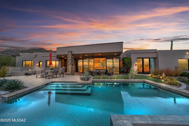 pool at dusk with a fire pit and a patio