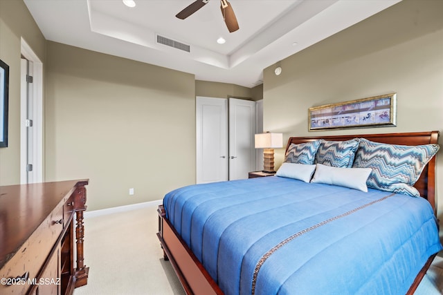 carpeted bedroom with ceiling fan and a tray ceiling