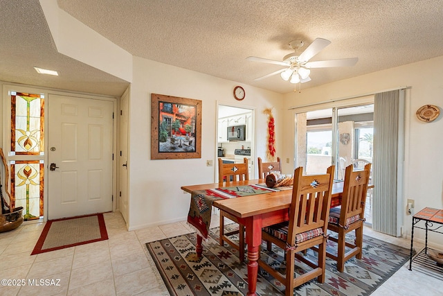 tiled dining area with ceiling fan and a textured ceiling