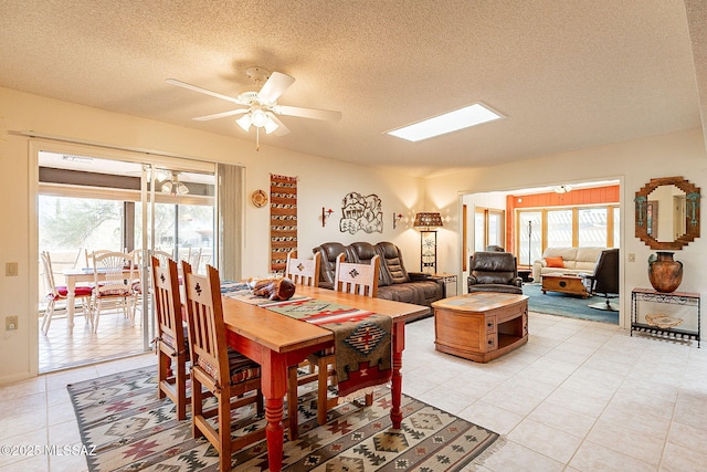 dining area with a healthy amount of sunlight, a textured ceiling, ceiling fan, and a skylight