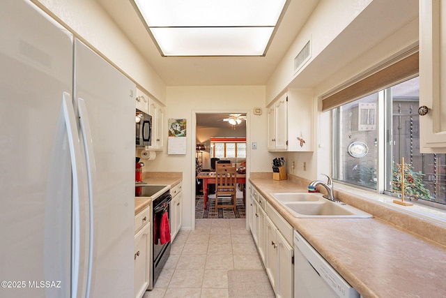 kitchen with sink, white cabinets, light tile patterned floors, ceiling fan, and black appliances