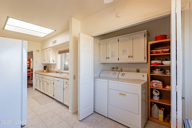 laundry room featuring cabinets, sink, light tile patterned floors, and washer and clothes dryer