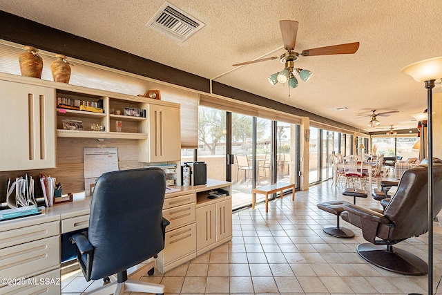 tiled home office featuring ceiling fan, built in desk, and a textured ceiling