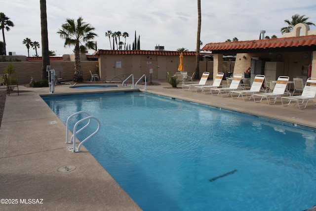 view of swimming pool featuring a hot tub and a patio