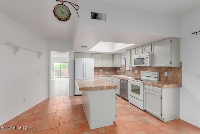 kitchen featuring white appliances, tasteful backsplash, a kitchen island, and sink