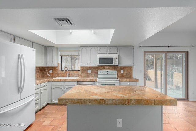 kitchen with backsplash, sink, a kitchen island, and white appliances