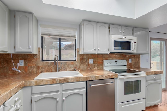 kitchen with plenty of natural light, white appliances, sink, and tasteful backsplash