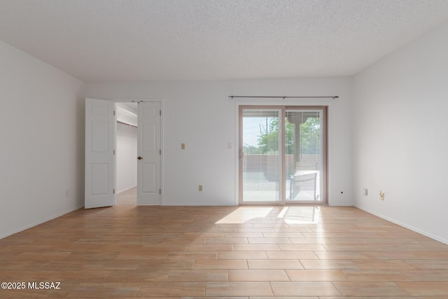 spare room featuring light hardwood / wood-style flooring and a textured ceiling