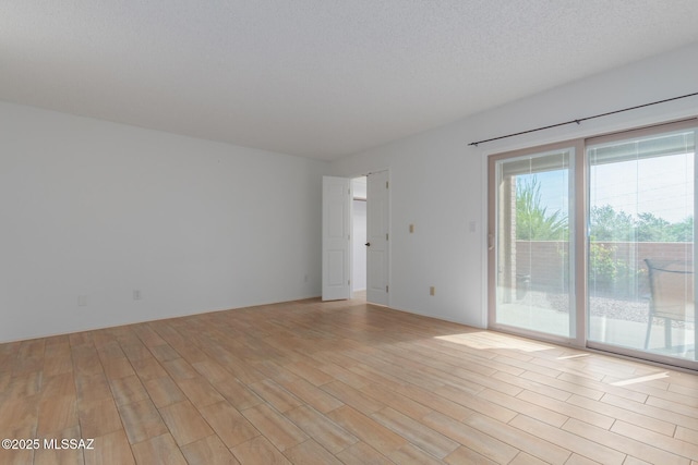 unfurnished room with light wood-type flooring and a textured ceiling