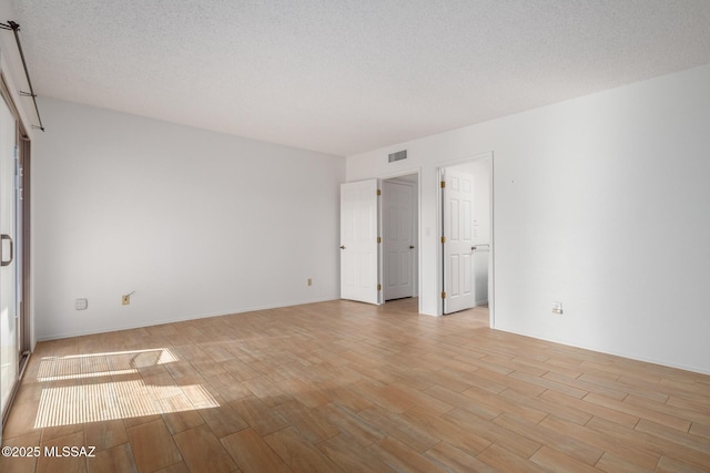 unfurnished bedroom with light wood-type flooring and a textured ceiling