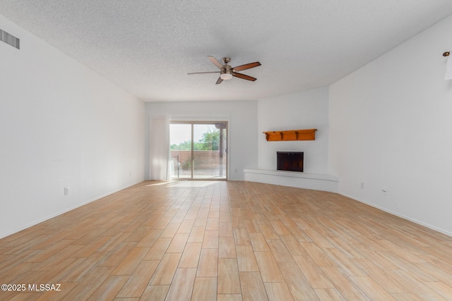 unfurnished living room with a textured ceiling, light hardwood / wood-style floors, and ceiling fan