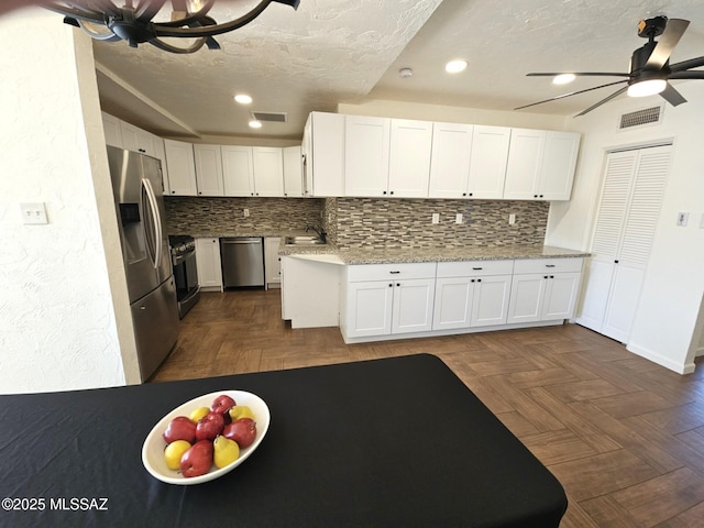 kitchen featuring stainless steel appliances, dark parquet flooring, white cabinets, and light stone counters