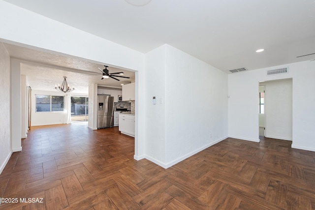 spare room featuring ceiling fan with notable chandelier and dark parquet floors