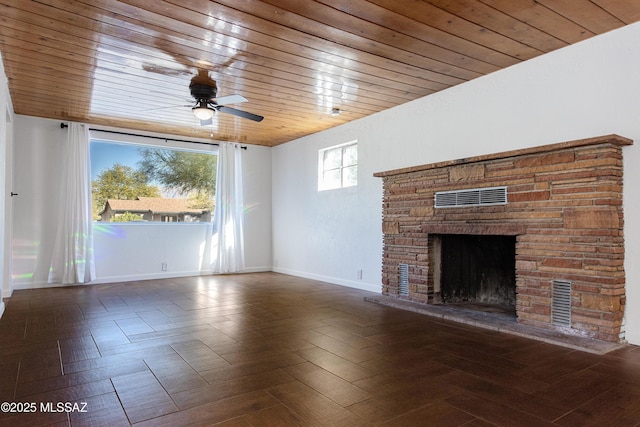 unfurnished living room with wood ceiling, a stone fireplace, dark parquet flooring, and ceiling fan