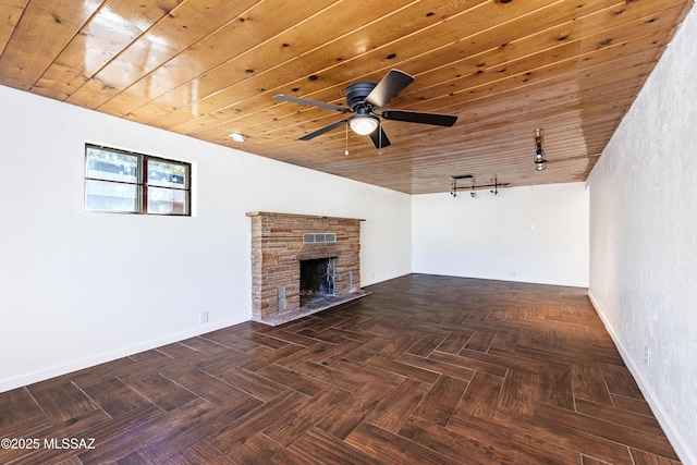 unfurnished living room with wood ceiling, ceiling fan, a fireplace, dark parquet floors, and track lighting