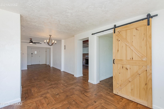 empty room featuring a fireplace, dark parquet flooring, ceiling fan with notable chandelier, and a textured ceiling