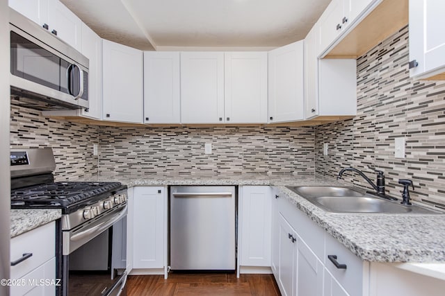 kitchen with appliances with stainless steel finishes, sink, dark parquet floors, and white cabinets