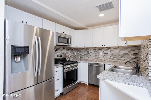 kitchen with tasteful backsplash, white cabinetry, dark parquet flooring, and light stone counters